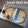 A small wall box for 4 fibres is shown with a cable entry to the left. Fibres are routed clockwise around the inside and spliced to fibre pigtails which end in SC connectors and in line adapters. SC patch cords would connect to the other side of the adapters and then exit the box to connect to LAN equipment